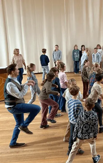 IVC singer leading primary-school children in a movement exercise during a Music Pathways workshop